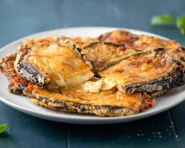 Melanzane contorno dorate e filanti, un piatto invitante con formaggio fuso e basilico fresco.