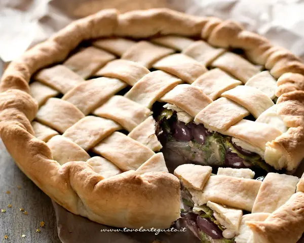 Pizza di scarola con un intreccio dorato di pasta e un ripieno invitante di verdure e olive.
