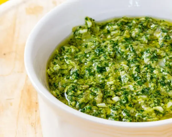 Una ciotola bianca piena di vibrante salsa verde, perfetta per accompagnare i tuoi piatti. Questa ricetta salsa verde è un'esplosione di freschezza.