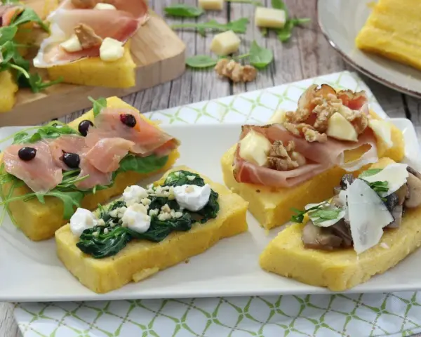 Deliziosi crostini di polenta misti: con salmone affumicato, spinaci e ricotta, prosciutto e noci, o funghi e parmigiano.