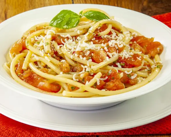 Un piatto invitante di pasta alla carrettiera, con pomodoro fresco, basilico e formaggio grattugiato.