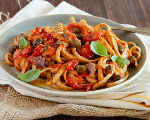 Pasta con sugo rosso, olive, acciughe e basilico, un assaggio di **stroncatura calabrese**.