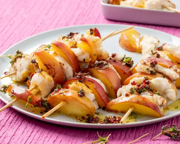 Spiedini per aperitivo veloci con pesche succose e bocconcini di pesce bianco, conditi con erbe aromatiche e olio.