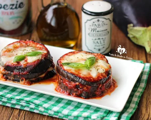 Deliziosa parmigiana di melanzane grigliate, con strati di melanzane, sugo e formaggio filante, guarnita con basilico fresco.