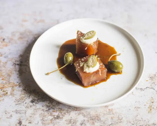 Cubetti di tonno vitellato con salsa bruna, capperi e una quenelle di maionese.