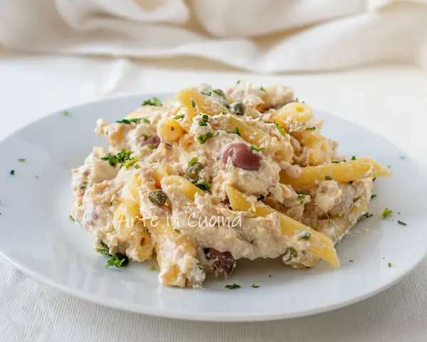Piatto di pasta cremosa con tonno, olive nere e capperi, guarnita con prezzemolo fresco. Un classico della pasta tonno e olive.