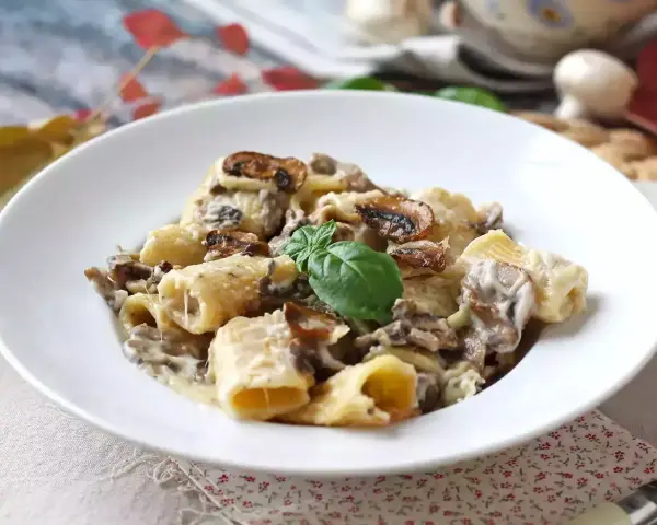 Piatto invitante di pasta panna e funghi, guarnito con basilico fresco.