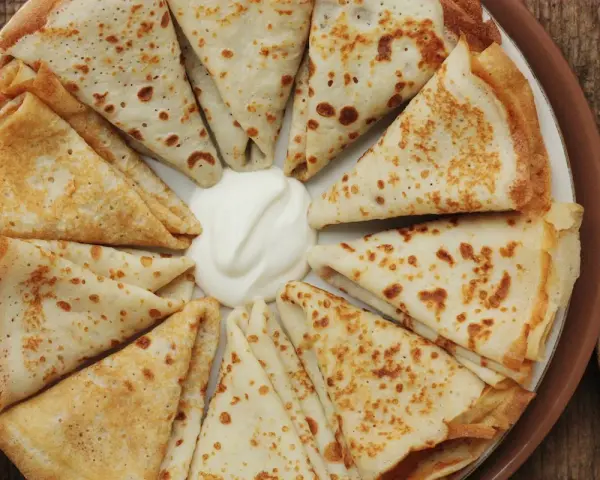 Crespelle piegate a spicchi, con al centro una generosa cucchiaiata di panna acida. Un'idea su crespelle come farcirle per un pasto delizioso.