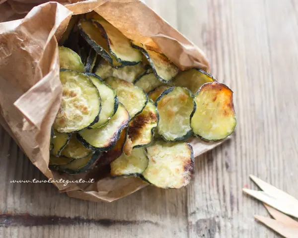 Delizioso contorno di zucchine fritte, croccanti e dorate, servite in un sacchetto di carta.