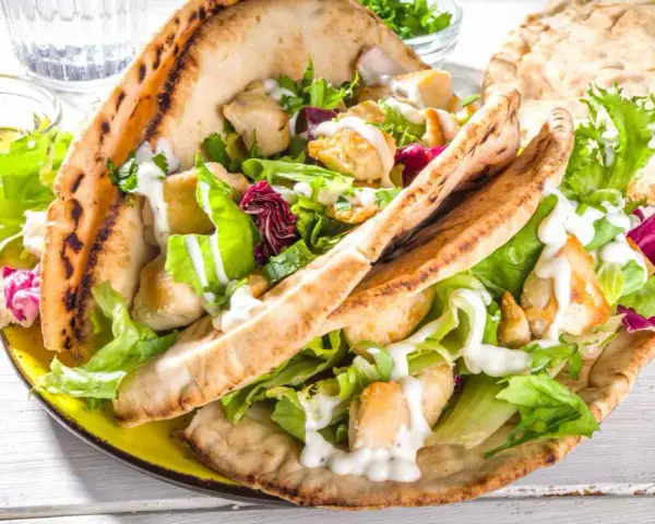 Pita ripiena di pollo e insalata fresca, condita con una cremosa salsa yogurt.