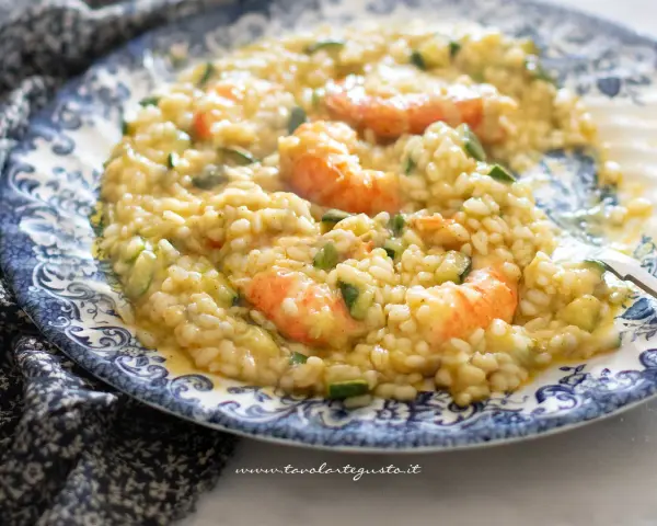 Un cremoso risotto zucchine e gamberetti, servito su un piatto decorato.