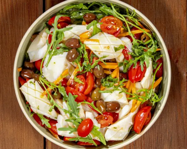 Insalata di calamari fresca con pomodorini, olive, rucola e carote julienne, un piatto leggero e saporito.