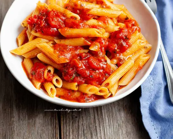Piatto invitante di penne all'arrabbiata, con la pasta condita da un sugo rosso piccante e saporito.