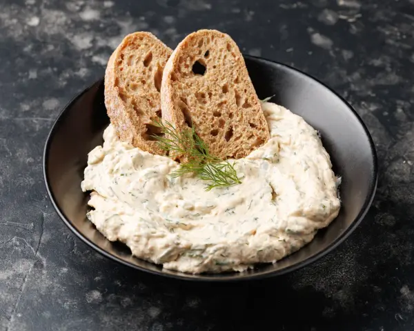Mousse di tonno cremosa con erbe aromatiche, guarnita con aneto e servita con fette di pane integrale tostato.