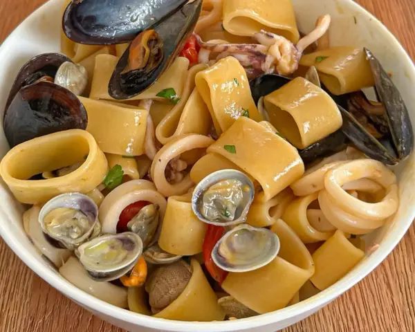 Calamarata allo scoglio ricca di cozze, vongole e anelli di calamaro, un piatto di mare invitante.