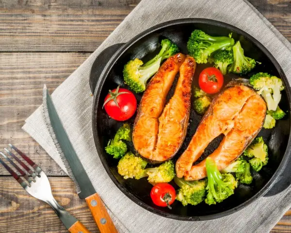 Due tranci di salmone succulento, cotti in padella, accompagnati da broccoli croccanti e pomodorini freschi. Un piatto sano e gustoso.