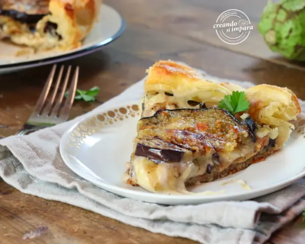Una fetta di torta salata con melanzane, formaggio filante e pasta sfoglia dorata, guarnita con prezzemolo fresco.