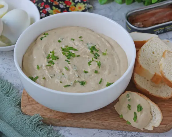 Una cremosa salsa tonnata con maionese, guarnita con erba cipollina, pronta per essere gustata con pane tostato e uova sode.