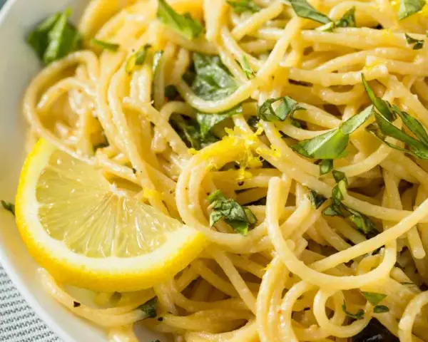 Spaghetti al limone, un classico della ricetta della Costiera Amalfitana, guarniti con scorza di limone e basilico fresco.