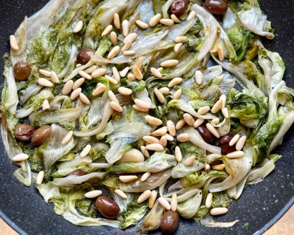Scarola in padella con olive e pinoli, un contorno saporito e leggero.