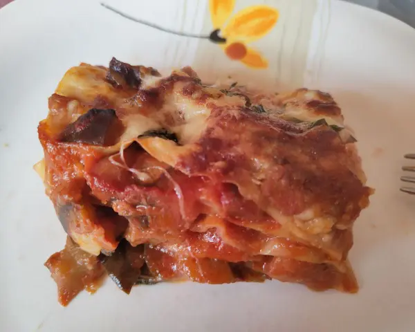 Una fetta di lasagna di melanzane, ricca e saporita, con strati di melanzane, pomodoro e formaggio filante.