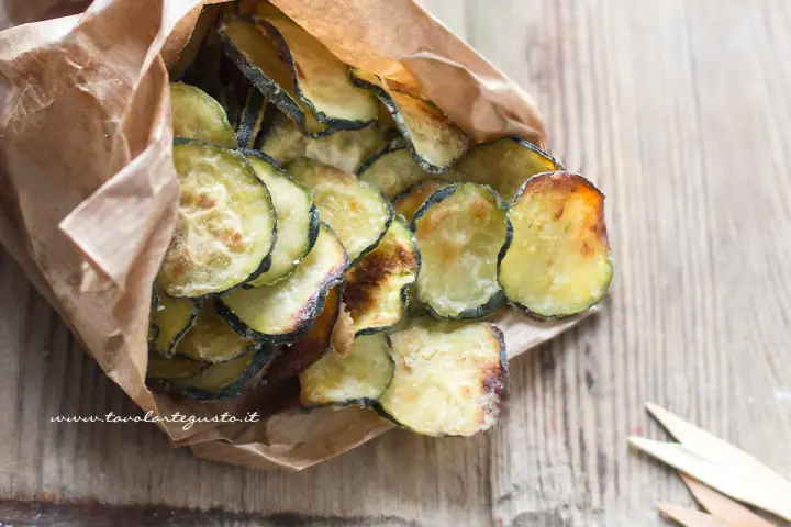 Delizioso contorno di zucchine fritte, croccanti e dorate, servite in un sacchetto di carta.