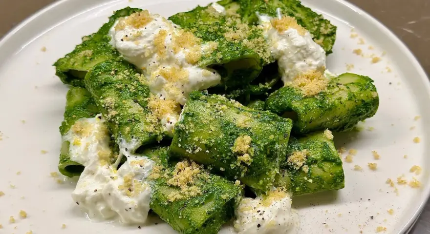 Paccheri conditi con un vibrante pesto di cavolo nero, arricchiti da ricotta cremosa e una spolverata di pangrattato croccante.