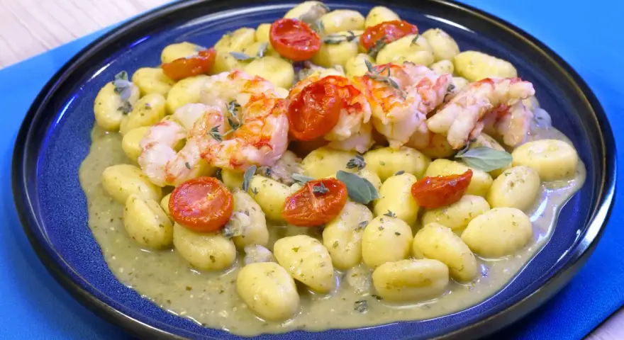 Gnocchi con pesto, gamberi succulenti e pomodorini confit. Un piatto che celebra i sapori del mare e della terra.