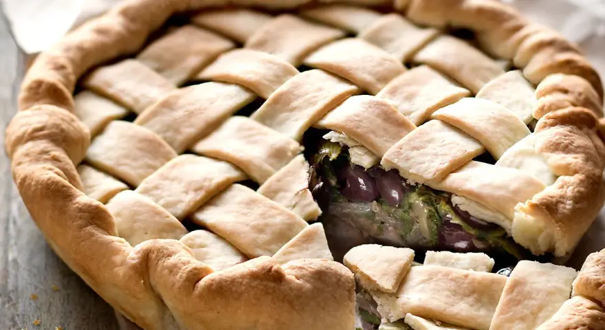 Pizza di scarola con un intreccio dorato di pasta e un ripieno invitante di verdure e olive.