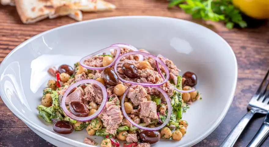 Deliziosa insalata di ceci e tonno con olive nere, cipolla rossa e prezzemolo fresco. Un piatto leggero e gustoso.