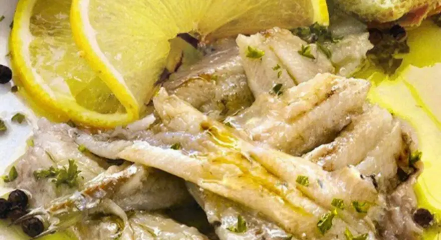 Alici in padella, succulente e dorate, condite con limone fresco, prezzemolo e pepe nero. Un piatto semplice e gustoso.