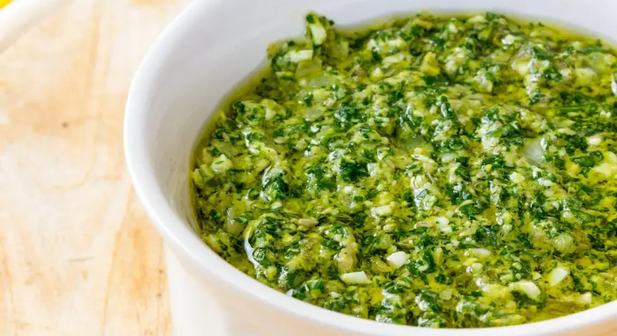 Una ciotola bianca piena di vibrante salsa verde, perfetta per accompagnare i tuoi piatti. Questa ricetta salsa verde è un'esplosione di freschezza.