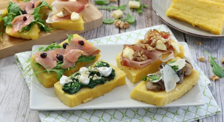 Deliziosi crostini di polenta misti: con salmone affumicato, spinaci e ricotta, prosciutto e noci, o funghi e parmigiano.