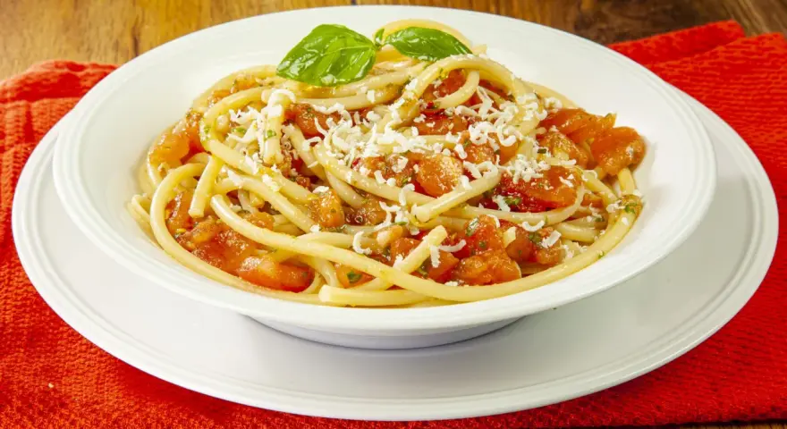 Un piatto invitante di pasta alla carrettiera, con pomodoro fresco, basilico e formaggio grattugiato.