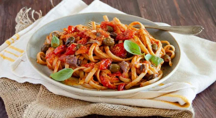 Pasta con sugo rosso, olive, acciughe e basilico, un assaggio di **stroncatura calabrese**.