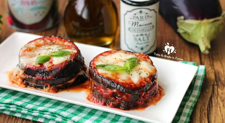 Deliziosa parmigiana di melanzane grigliate, con strati di melanzane, sugo e formaggio filante, guarnita con basilico fresco.