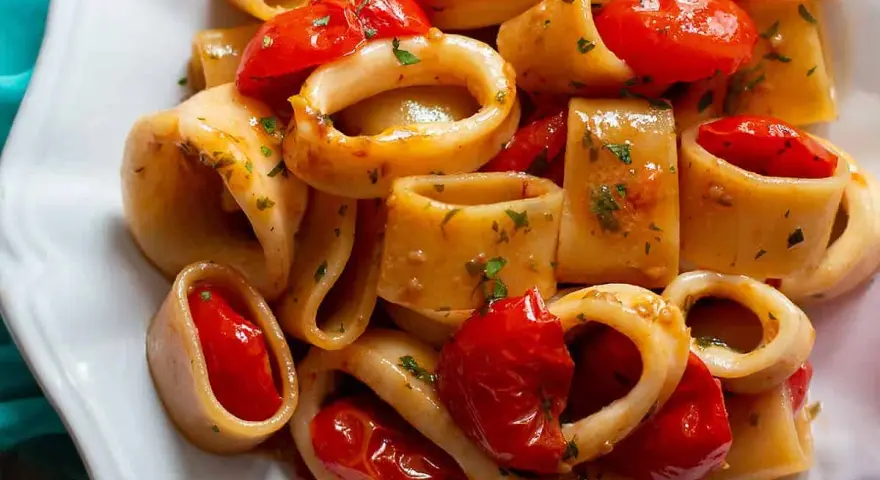 Un invitante sugo di pesce con anelli di calamaro e pomodorini, guarnito con prezzemolo fresco.