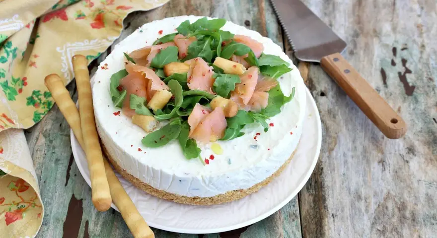 Deliziosa cheesecake salata con salmone affumicato, rucola e crostini. Perfetta per un aperitivo o antipasto elegante.