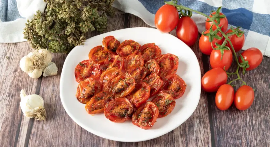Pomodorini confit in friggitrice ad aria, conditi con erbe aromatiche e aglio. Un contorno saporito e facile da preparare.