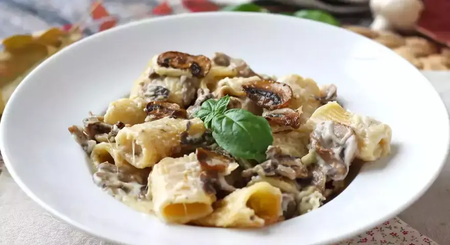 Piatto invitante di pasta panna e funghi, guarnito con basilico fresco.