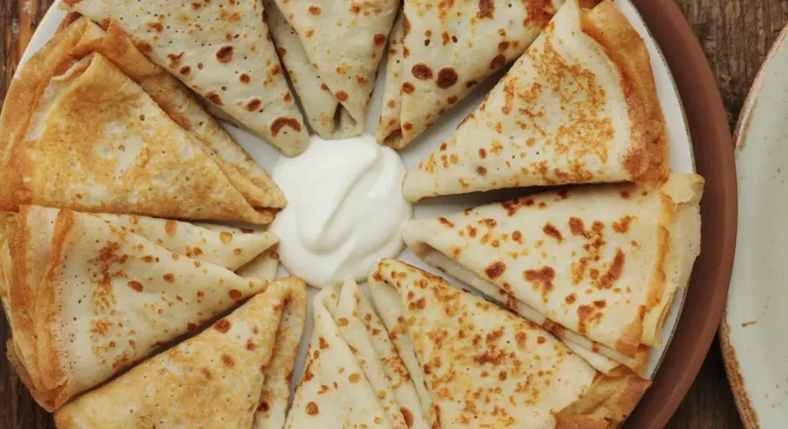 Crespelle piegate a spicchi, con al centro una generosa cucchiaiata di panna acida. Un'idea su crespelle come farcirle per un pasto delizioso.
