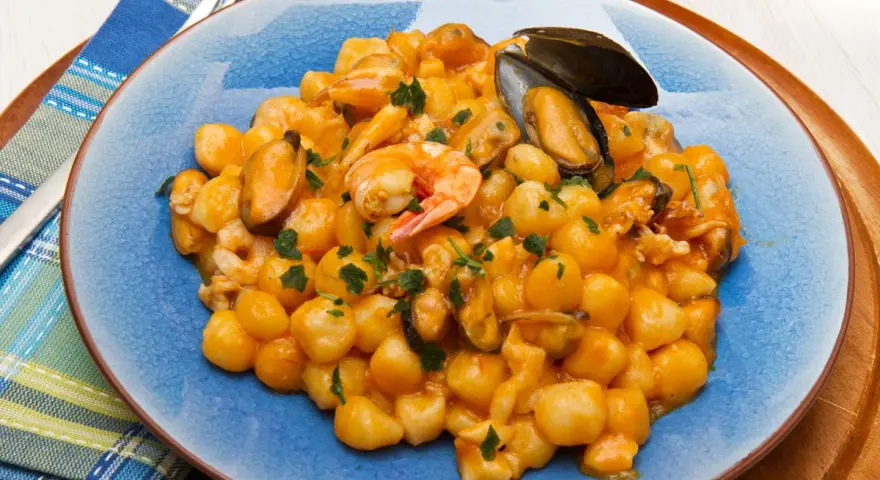Gnocchi di patate con frutti di mare, gamberi e cozze, guarniti con prezzemolo fresco.