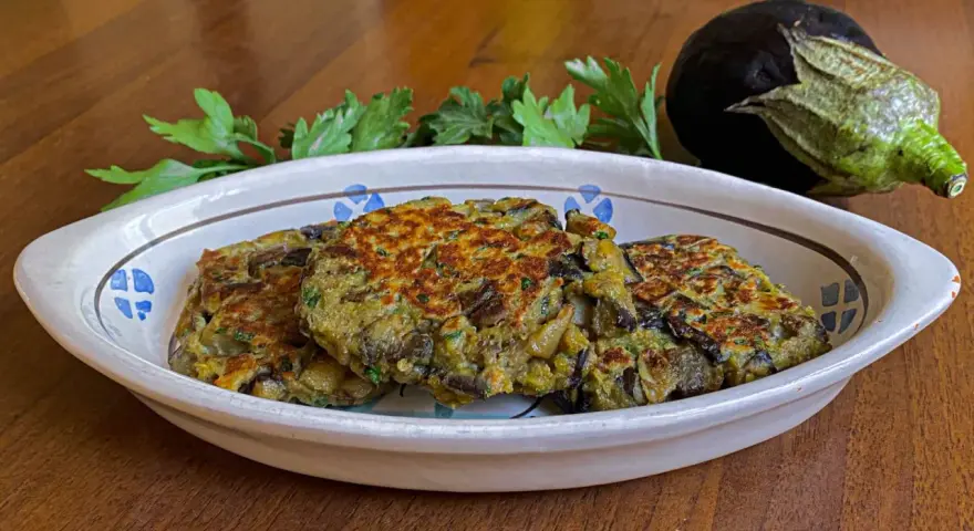Tre deliziosi hamburger di melanzane dorati, guarniti con prezzemolo fresco, in un piatto rustico.