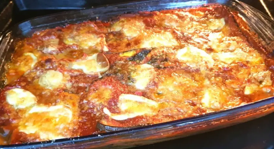 Un invitante pasticcio di melanzane appena sfornato, con strati dorati di formaggio fuso e salsa rossa.