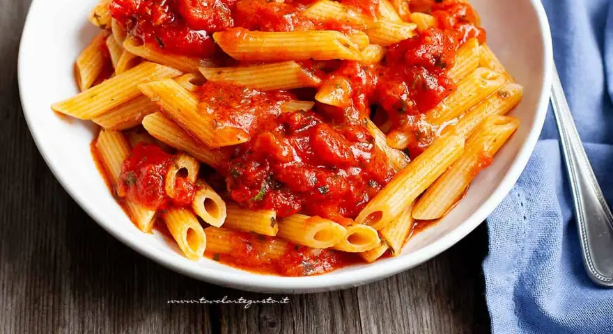 Piatto invitante di penne all'arrabbiata, con la pasta condita da un sugo rosso piccante e saporito.