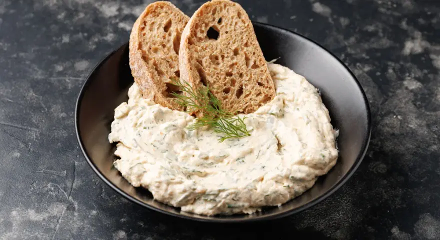 Mousse di tonno cremosa con erbe aromatiche, guarnita con aneto e servita con fette di pane integrale tostato.