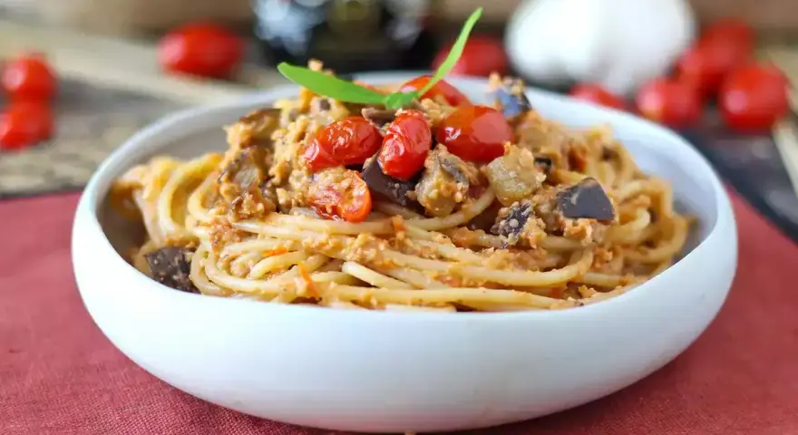 Spaghetti al tonno ricetta della nonna: un piatto gustoso con melanzane, pomodorini e basilico.