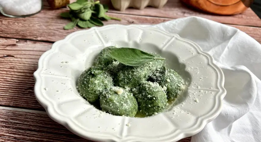 Gnudi verdi, una deliziosa ricetta con spinaci e ricotta, guarniti con parmigiano e una foglia di salvia.