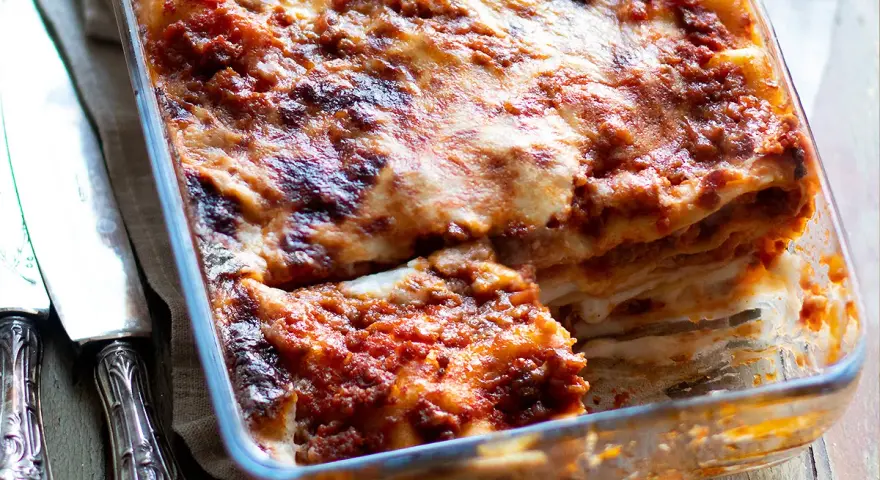 Lasagna alla bolognese appena sfornata, con strati dorati e ripieno succulento, pronta per essere gustata.