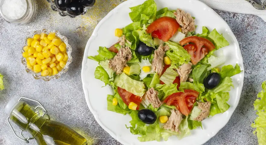 Deliziosa insalata di tonno con lattuga croccante, pomodoro, mais e olive nere. Un piatto fresco e leggero, perfetto per ogni occasione.